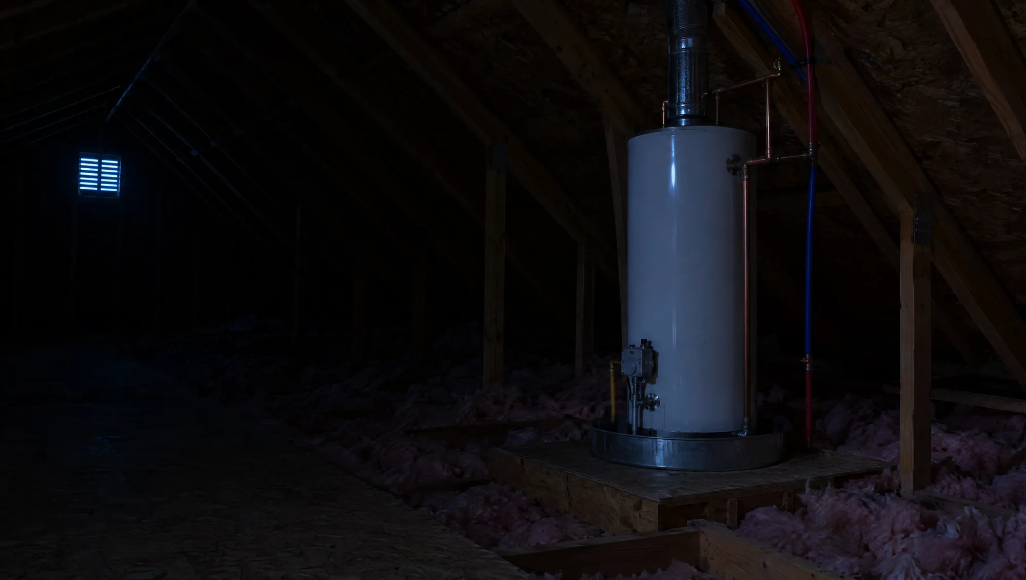 A gas water heater in a dark attic